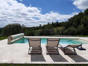 two chairs and a table next to a swimming pool at Les Côtes - Charming holiday home with heated swimming pool in Palluaud