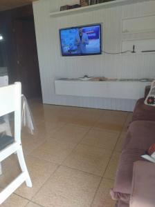 a living room with a tv on a wall at Pousada 03 do vô Bi in São Francisco do Sul