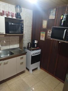 a small kitchen with a stove and a microwave at Pousada 03 do vô Bi in São Francisco do Sul