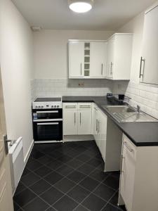 a kitchen with white cabinets and a black counter top at Doncaster City Centre Immaculate 1 Bedroom flat in Doncaster