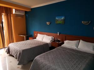 a hotel room with two beds and a blue wall at Hotel Delfin Rosado in Puyo +5 photos