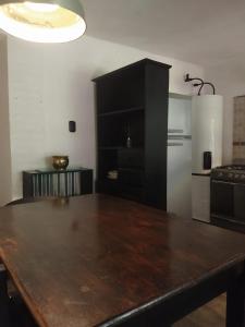 a kitchen with a wooden table and a black cabinet at Hospedaje JosEva in Unquillo +27 photos