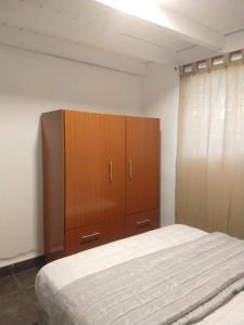 a bedroom with a bed and a wooden cabinet at Hospedaje JosEva in Unquillo