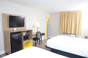 a hotel room with two beds and a flat screen tv at Days Inn by Wyndham Pittsburgh in Pittsburgh