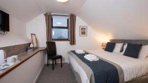 a bedroom with a bed with a chair and a window at Ferry Inn in Stromness