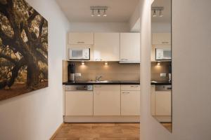 a kitchen with white cabinets and a painting on the wall at Haus Kristall inkl der SUPER SOMMER CARD im SOMMER 2026 in Serfaus