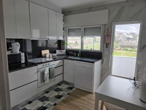 a kitchen with white cabinets and a table and a window at Ninho D`ouro in Peso da Régua