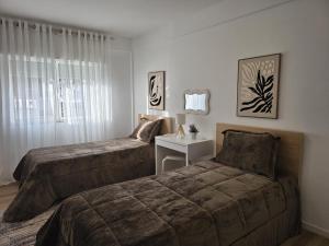 a bedroom with two beds and a table and a window at Ninho D`ouro in Peso da Régua