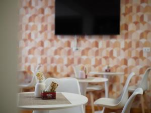 a room with tables and white chairs and a flat screen tv at Oasi Santa Rosa in Rome