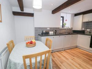 a kitchen with a table with a bowl of fruit on it at Ivy Cottage in Abergele