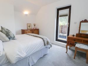 a bedroom with a bed and a mirror and a dresser at Ivy Cottage in Abergele