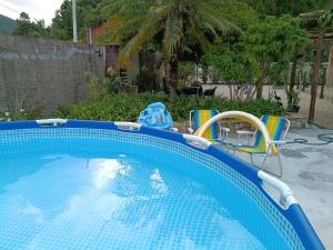 a blue swimming pool with chairs in a yard at Casa MonteFlor - Refúgio onde a vida desacelera com gentileza in Governador Celso Ramos