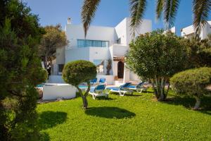a white house with chairs and trees in the yard at Villa Mar Gran in Cacla D'or