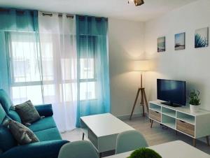 a living room with a blue couch and a tv at PLAYA Y PISCINA Intiyan PONDOS in Almuñécar