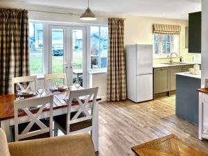 a kitchen and dining room with a table and a refrigerator at Pine View Cottage in Filey