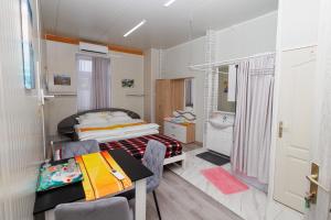 a bedroom with a bed and a table and a sink at Békési Apartmanok in Békés