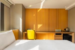 a bedroom with a bed and a yellow chair at CHECK inn Taichung Wenxin Zhongqing in Taichung +94 photos