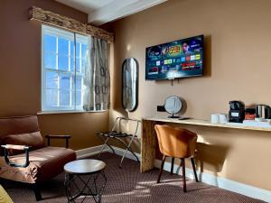 a room with a bar with a tv and chairs at The Crescent Guest House in York