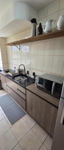 a kitchen with a sink and a microwave at Apto térreo aconchego e localização central in Santa Rosa