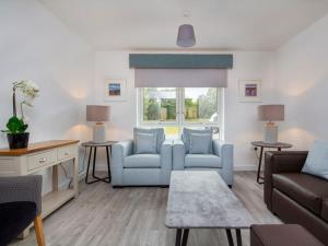 a living room with blue furniture and a window at Oakwood in Aviemore