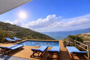 a swimming pool with chairs and a view of the ocean at Amar Seaside in Ksamil