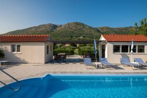 a pool with chairs and a house with mountains in the background at Villa Liberty 2 in Cavtat