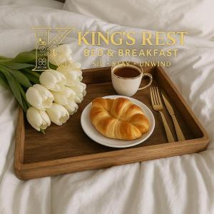 a tray with a croissant and a cup of coffee and flowers at Kings Rest Bed And Breakfast in Gaborone