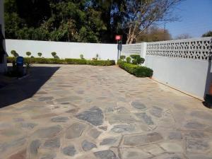 a white fence and a stone walkway next to a driveway at Kings Rest Bed And Breakfast in Gaborone