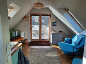 a living room with a blue chair and a sliding glass door at The Wee Loft in Carrbridge