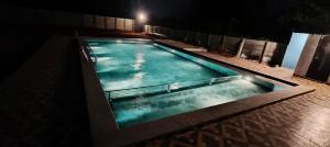 a swimming pool at night with the lights on at La nature in Pondicherry