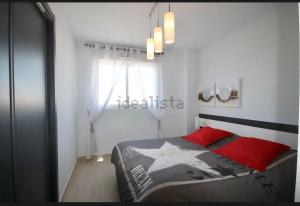a bedroom with a bed with red pillows and a window at résidence 2 chambres avec piscine proche mer in Orihuela Costa +24 photos