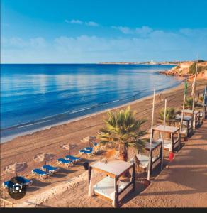 a row of tables and chairs on a beach at résidence 2 chambres avec piscine proche mer in Orihuela Costa