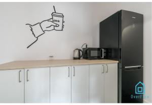 a kitchen with a refrigerator and a hand holding a cup at Sunlight Room - 15 min to Old Town Gdansk in Gdańsk +8 photos