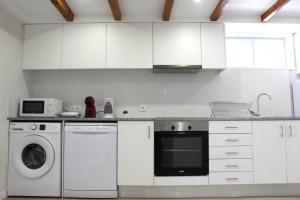 a kitchen with white cabinets and a washer and dryer at 1000Jo Apartment T2 in Gulpilhares