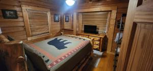 a bedroom in a log cabin with a bed and a television at The Bears Den in Gatlinburg +2 photos