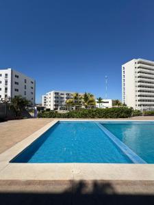 a swimming pool in front of two tall buildings at Fantástico Depa en BLUU con Playa Artificial ! in Mazatlán