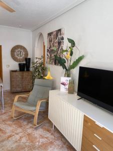 a living room with a flat screen tv and a chair at Angeleyes in San Pedro del Pinatar