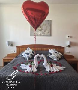 two swans with a heart balloon on a bed at Goldvilla Apartman in Zalakaros