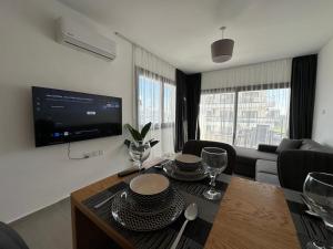 a living room with a table and a tv at Caesar Resort Atilius in Trikomo