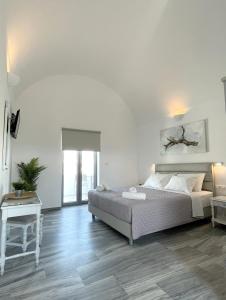a white bedroom with a bed and a table at DL Santorini in Monolithos +90 photos