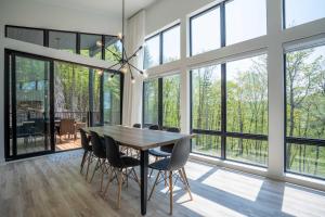 a dining room with a table and chairs and windows at Chalet du Golf avec Spa in Saint-Faustin
