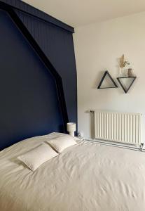 a bedroom with a large bed with a blue wall at Chez Joséphine et Pierre in Cassel +4 photos