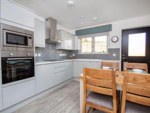 a kitchen with white cabinets and a table with chairs at Oakwood in Aviemore +15 photos