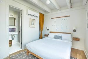 a bedroom with a white bed and a bathroom at The Windrose in Savannah