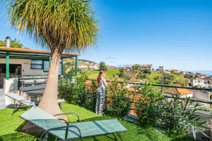 a woman standing on the roof of a house with a palm tree at Johns Villa by Homie in Canhas