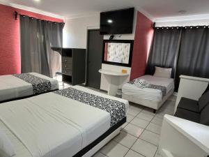a hotel room with two beds and a television at Hotel & Suites Bausan in Boca del Río