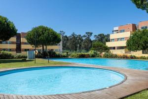 a large pool in a park with buildings in the background at Aurora do Furadouro II in Ovar