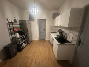 a kitchen with white cabinets and a wooden floor at Chambre privee dans une maison 2 in Aulnay-sous-Bois