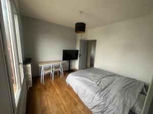 a bedroom with a bed and a table and a television at Chambre privee dans une maison 2 in Aulnay-sous-Bois