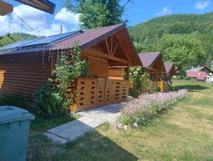 a log cabin with a fence and flowers at Căsuțele Camping AliMar in Tîrsa